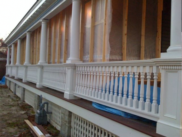 View of house porch with turned white wood balusters and columns and square newels.